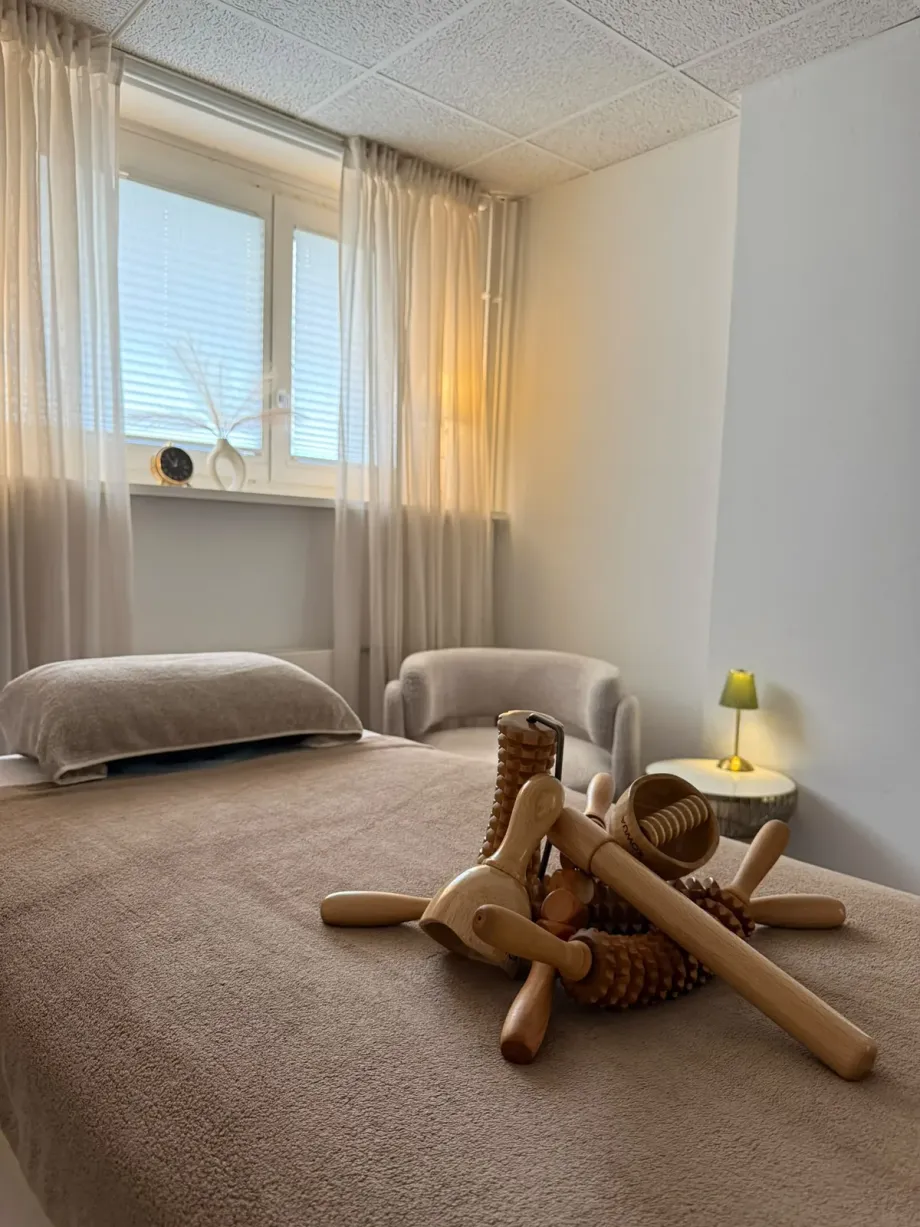 Die bezogene Behandlungsliege mit den Holzwerkzeugen darauf, am Fenster.