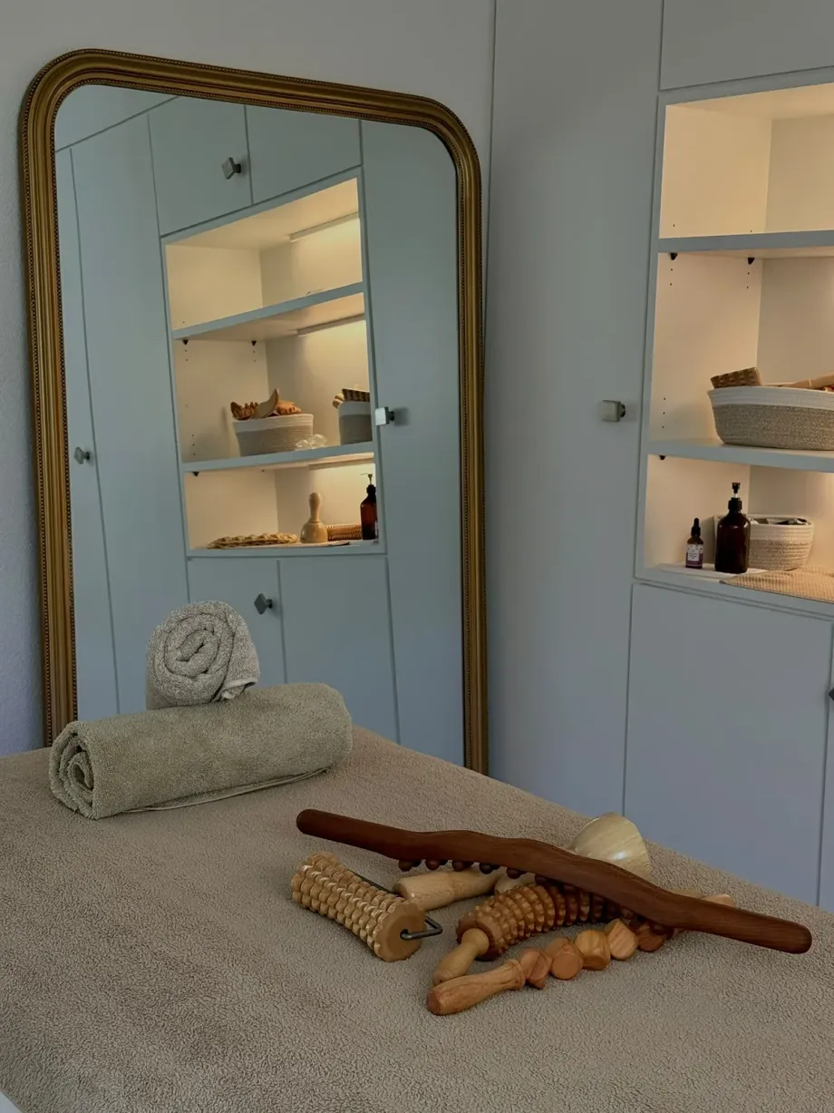 Die Liege vor dem hohen Spiegel, mit beleuchtetem Regal und Holzwerkzeugen.